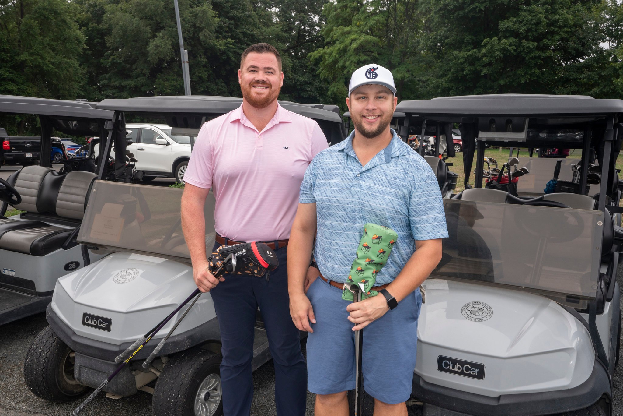 Two men smiling in front of golf carts